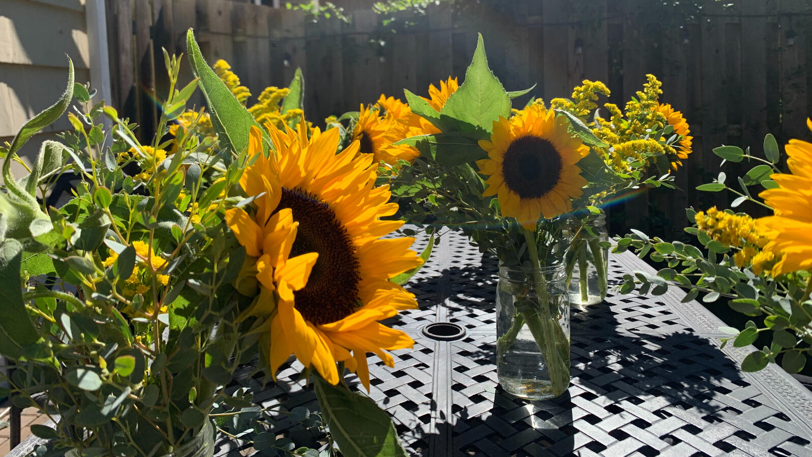 A black outdoor table with vases of sunlowers.