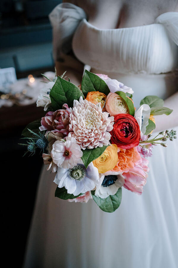 A full body shot of a woman wearing a wedding dress and holding a bridal bouquet.