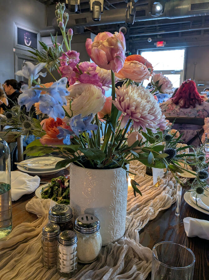 A table with a large floral arrangement with delphinium, mums, tulips and roses.