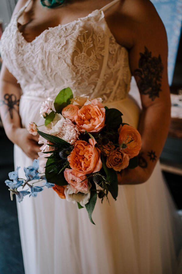 A full body shot of a woman wearing a wedding dress and holding a bridal bouquet.